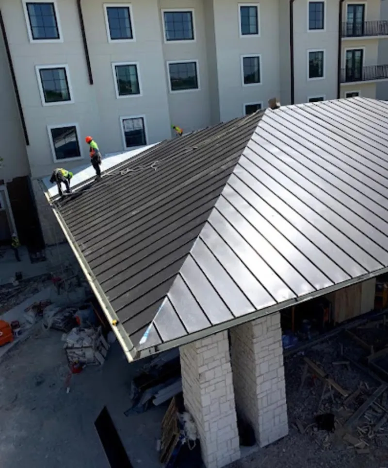 Crew installing standing seam metal roof panels on a commercial project in Westfield